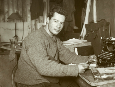 Black and white photograph of Apsley Cherry Garrard sat at a desk with a typewriter