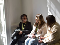 Three postgraduates chatting to each other at conference.