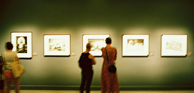 Two people looking at a picture in an exhibition gallery.