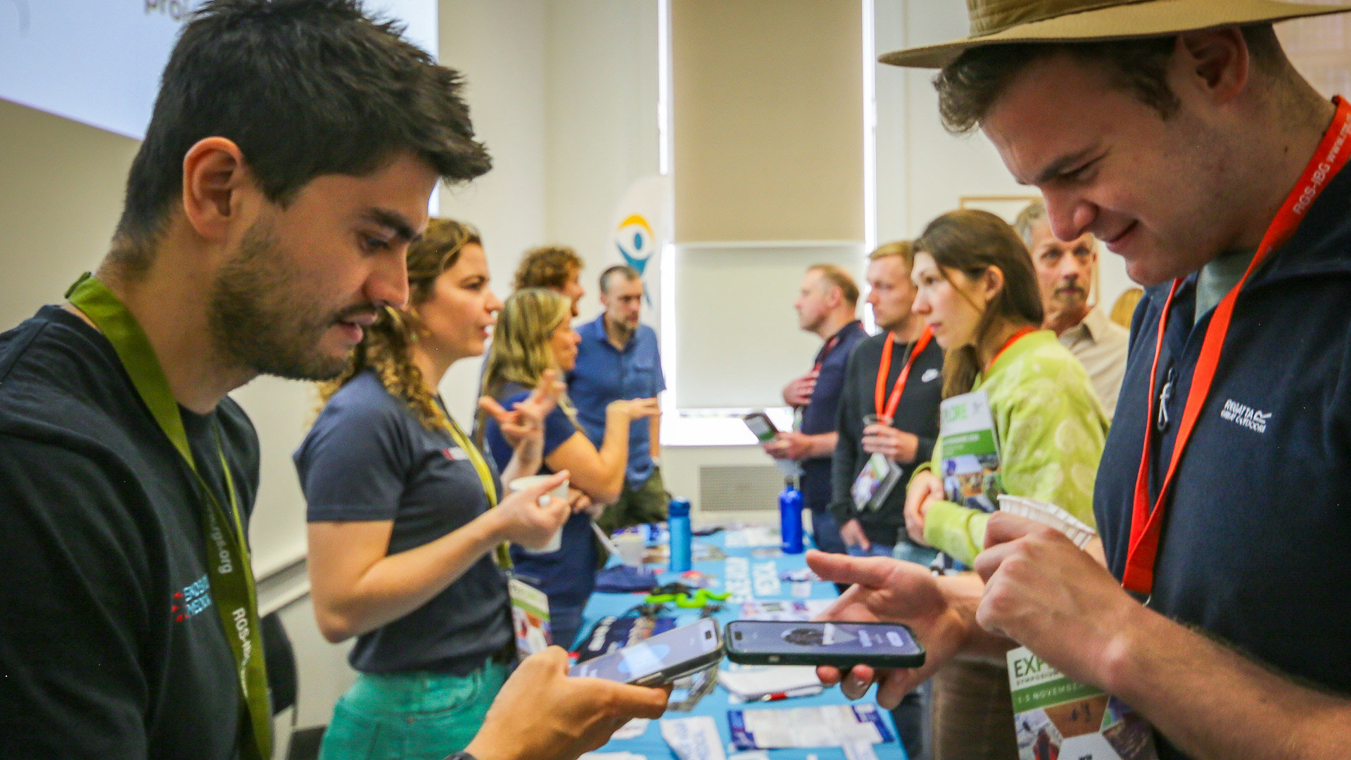 Attendees networking with phones in hand over an exhibitor stand.