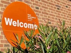Round, orange welcome sign at the Royal Geographical Society.