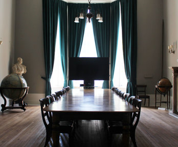 Stately looking meeting room with a large wooden table and several globes.