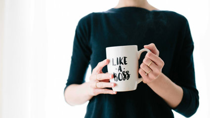 A person holding a mug that has 'like a boss' written on it.