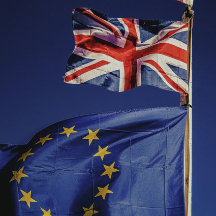A Union Jack flag and the flag of the EU flying on a blue background