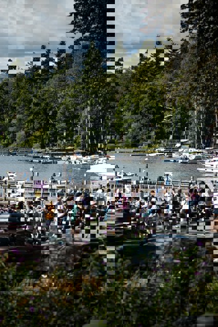 A view of Bowness with tourists and bpats on the lake