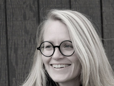 Person standing against a dark wooden panel background.