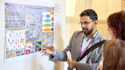 A person presenting his poster to conference delegates.