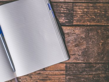 Open notebook and pen on a wooden table.