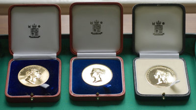 Three Society medals displayed in wooden boxes.