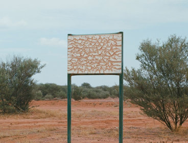 A map in the desert. Photograph titled 'A Thin Line Casts A Long Shadow'.