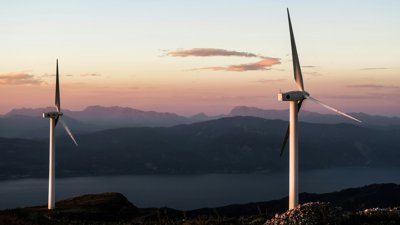 two wind turbines with mountain view at sunset