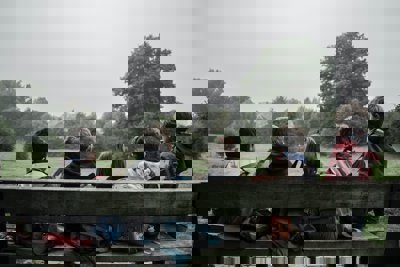 A gorup of children sitting on a bench looking at a field with trees