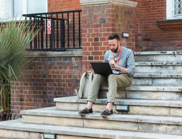 Person working on laptop on steps of the Royal Geographical Society.