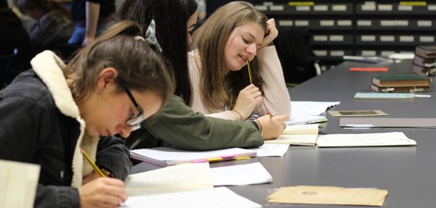Three people working with books at a table