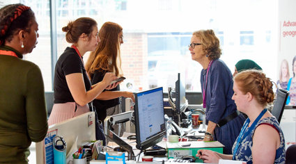 A conference attendee talking to a receptionist at the reception desk.