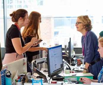 A conference attendee talking to a receptionist at the reception desk.