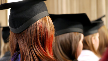 Back of heads of three people wearing square university graduation caps.