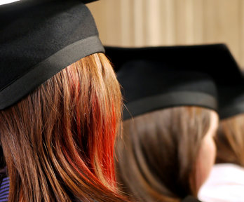 Back of heads of three people wearing square university graduation caps.
