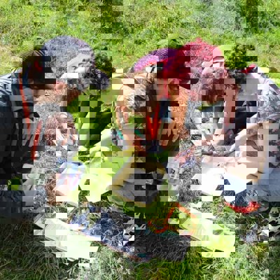 A group of teachers crouched around a sampling kit, testing the pH of something