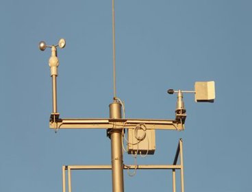 A gold anemometer on a blue sky background