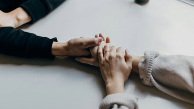 Close up of two pair of hands holding each other in a reassuring manner.