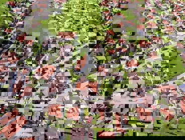 An aerial view of a town with green grass and orange roofs