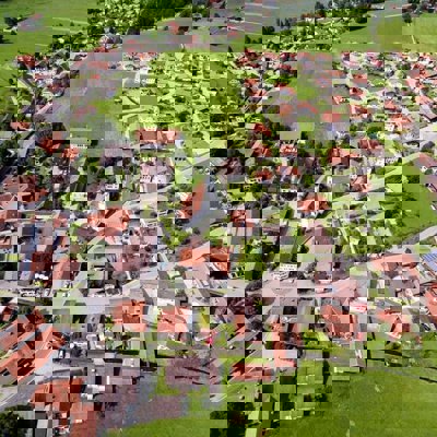 An aerial view of a town with green grass and orange roofs