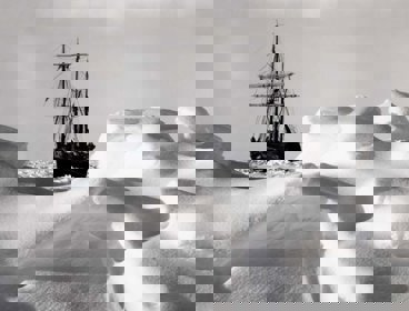 A black boat can be seen stuck within the white ice backdrop. The ice is undulating and tinged grey by shadows