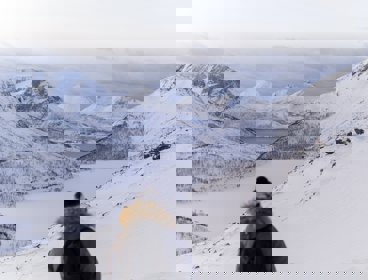 A person looking over a snowy scene of mountains and valleys