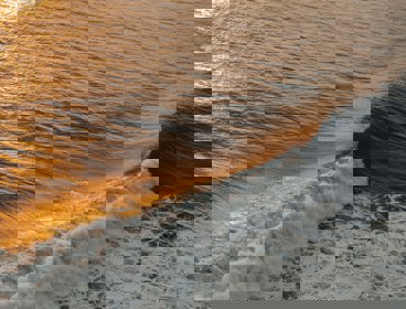 Waves at the shoreline with a sunset sky reflecting on the water