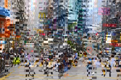 A chinese street that is busy with people, Shops and a McDonalds sign can be seen