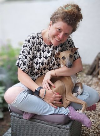 Vanessa Pilley seated and holding a dog while posing for a photo.