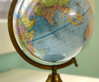 A globe sits on a white table next too a window. The background is blurred