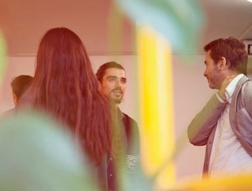 People gather together in a room, chatting and networking.