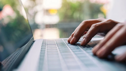 Closeup image of a person typing on laptop computer keyboard.