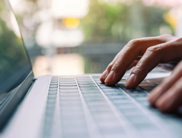 Closeup image of a person typing on laptop computer keyboard.