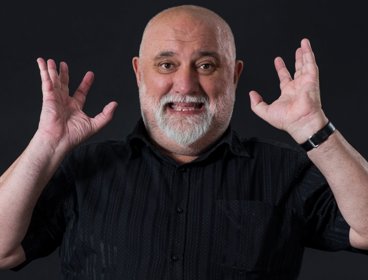 Alexei Sayle against black background.