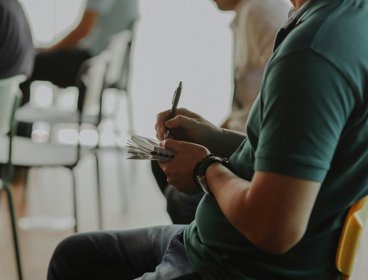Person sat on chair writing in notebook.
