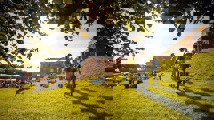 University of Sussex campus showing buildings and students sitting and walking on the grass.