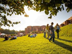 University of Sussex campus showing buildings and students sitting and walking on the grass.