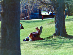 A person sitting in a lawn chair working on a laptop.