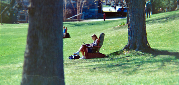 A person sitting in a lawn chair working on a laptop.