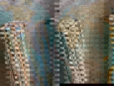 Map scrolls leaning up against a backdrop of another map