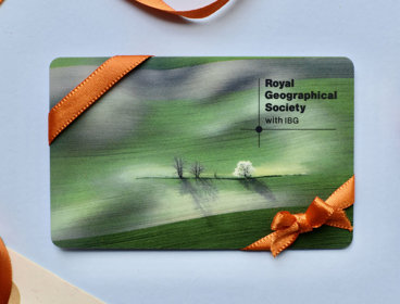 A membership card featuring a green landscape sits on a blue background with orange ribbon wrapped around it.