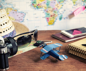 Collection of travel related items on a table with map in the background