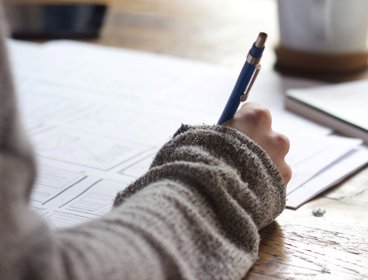 Person holding a pen and writing on a piece of paper