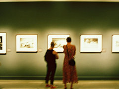 Two people looking at a picture in an exhibition gallery.