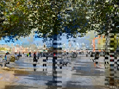 Public space by a river with people milling around