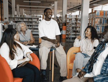 Group of five people sat in chairs in community library.