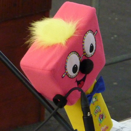 Timmy Mallet's mallet, a pink and yellow soft toy in the shape of a mallet with eyes, nose and mouth and glasses to look like the face of Timmy Mallet